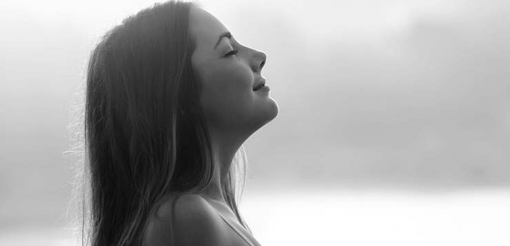 Backlight profile of a woman breathing deep fresh air in the morning sunrise isolated in white above